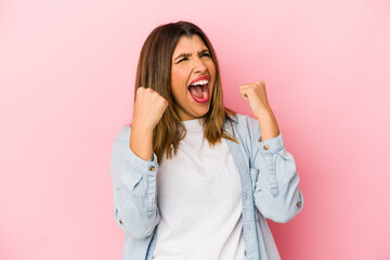 Young indian woman isolated on pink background raising fist after a victory, winner concept.