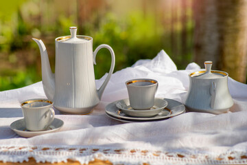 Coffee set on a white tablecloth on a sunny day. Outdoor, picnic, brunch, spring mood. Soft focus