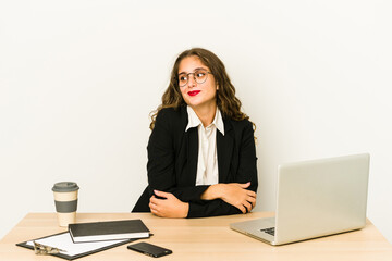 Young caucasian business woman working on her desktop isolated dreaming of achieving goals and purposes