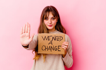 Young caucasian woman holding a We need a change placard isolated standing with outstretched hand...