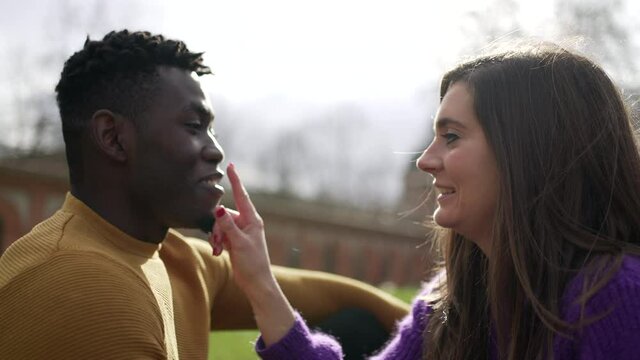 Girlfriend caressing and kissing boyfriend. Young interracial couple kiss