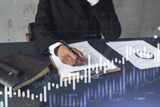 African American businesswoman in formal wear is signing the contract to invest money in stock market. Internet trading and wealth management. Forex and financial hologram chart. - Powered by Adobe