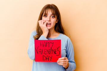 Fototapeta na wymiar Young caucasian woman holding a Happy Valentines day isolated biting fingernails, nervous and very anxious.