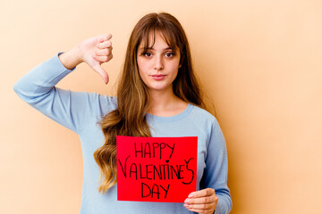 Fototapeta na wymiar Young caucasian woman holding a Happy Valentines day isolated showing a dislike gesture, thumbs down. Disagreement concept.