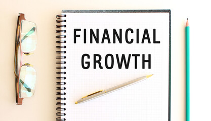 Notepad with text FINANCIAL GROWTH on a white background, near glasses and pencil.