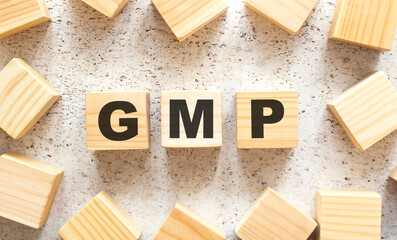 The word GMP consists of wooden cubes with letters, top view on a light background.