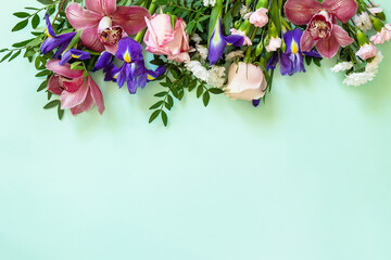Mother's day or birthday background. Spring beautiful bouquet of blooming rose, orchids, carnations and irises and spring greenery. Top view flat lay for greetings with space for text.