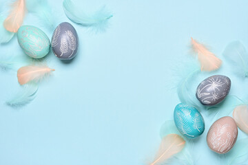 Happy easter greeting card template. Easter eggs and feathers on a blue pastel background. Flat lay, copy space