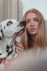 A young ginger woman with her Dalmation dog in the street.