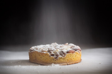 Close-up of an apple cake with nuts and powdered sugar on a dark background. Dark moody food photography style. Studio shot with copy space.