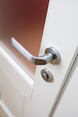 Obraz premium Close-up of a decorative element of the interior of the room - door fittings (door handle and lock). White door with glass