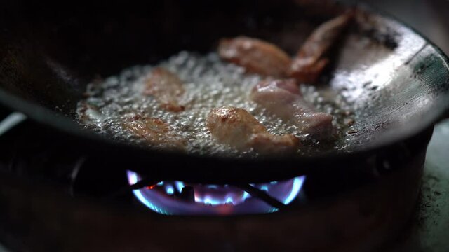 chicken meat cooking in hot oil on pan, unhealthy of fatty to people, splash and droplet of oil danger, gas fuel burnning to heat for fried or roast meat, raw fried chicken drumstick menu of delicious