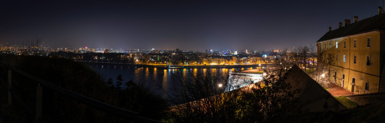 Fototapeta na wymiar Night panoramic view of Novi Sad, Serbia cityscape with bridges, Danube river and Petrovaradin fortress with beautiful colorful street lights from the town