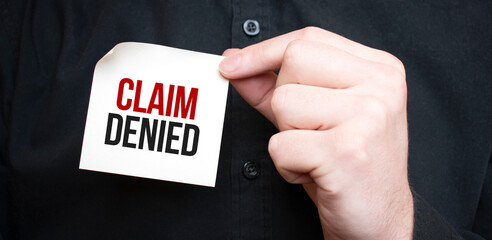 Businessman holding a card with text CLAIM DENIED,business concept