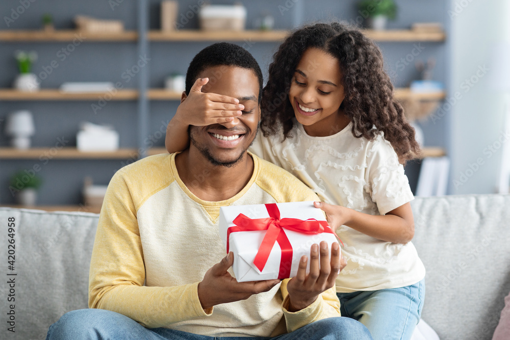 Wall mural happy little daughter giving present to her dad