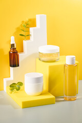 Set of natural cosmetics for face care serum, cream and micellar water on spesial podium yellow blurred background