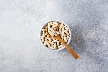 Closed collagen in capsules for diet food in a ceramic bowl on an old gray concrete background. Flat lay with copy space
