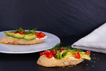 canapes of avocado wedges and a slice of tomato are laid out on a slice of baguette