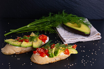 canapes, avocado wedges and tomato slices are laid out on a piece of baguette, avocado halves and...