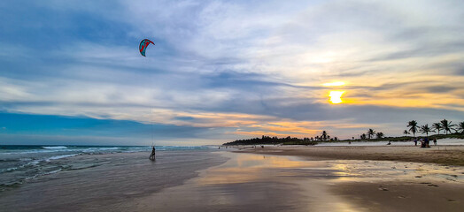 pôr do sol na praia com ondas e com céu colorido e tons de laranja 