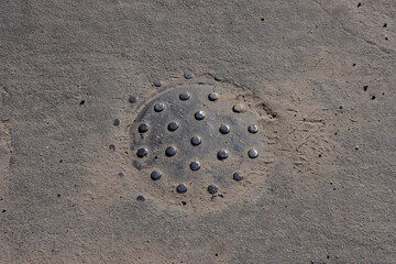 Close-up view of a small iron cover plate for a water valve in the asphalt of a city street