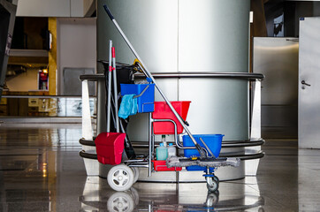 Cleaner cart in a public place. Mobile cart with cleaning products: mop, buckets for cleaning the...