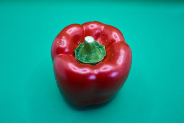 close up of a red bell pepper with a turquoise background