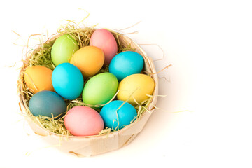 Easter concept. Painted eggs in bright juicy colors lie in the basket of the nest. White background,