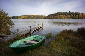 Naklejka na ściany i meble green boat on the lake shore on an autumn day