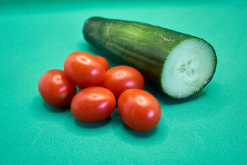 Close up of tomatoes and a sliced cucumber with a green background