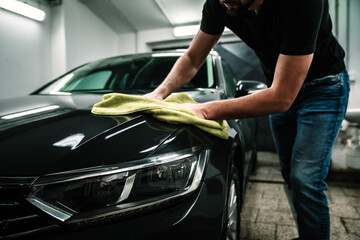 man cleans the car body with a towel. auto care