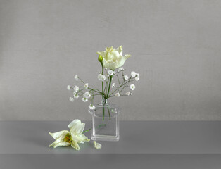Small bouquet with white flowers in a glass bottle. Minimalism.