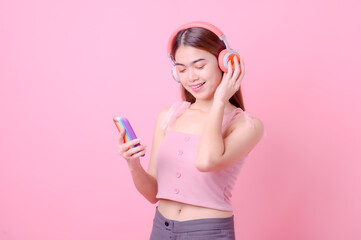 Beautiful Asian girls listen to music online via their mobile phone internet connection and dance happily