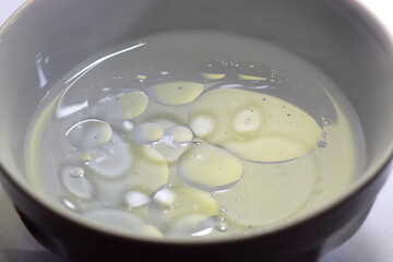 round oil stains on the surface of the water in the white bowl