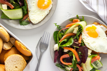 Fresh organic mesclun mix salad with cucumber, mozzarella and salmon, scrambled eggs and dry buns , delicious hearty breakfast