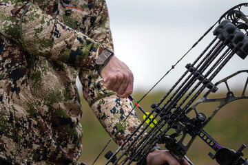 a man in a camouflage suit shoots with a professional bow and arrow, close-up shot