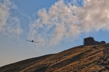 An airplane in the mountains flies near the old observatory