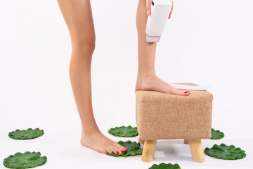 Hair removal. Fit young woman waxing her legs with a portable roll-on depilatory wax heater for...