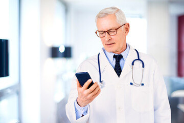 Male doctor text messaging while standing in doctor's room