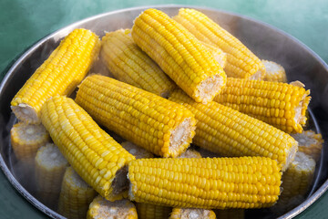 Street food. Ripe corn cobs are steamed in a large metal pot.