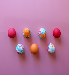 Happy Easter holiday! Colorful hand-painted Easter eggs in a decorative nest on pink background.