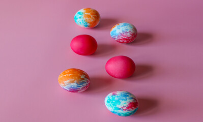 Happy Easter holiday! Colorful hand-painted Easter eggs in a decorative nest on pink background.