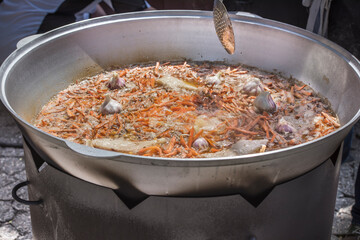 The preparation of traditional Uzbek pilaf with meat, carrots, garlic and spices