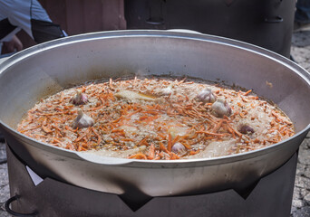 The preparation of traditional Uzbek pilaf with meat, carrots, garlic and spices