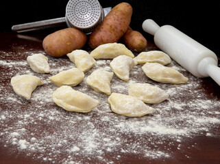 Ukrainian food, pierogui with potatoes, pasta roll and masher with dark background