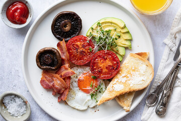 Breakfast with fried egg, tomatoes, mushroom, bacon and avocado
