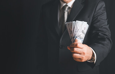 Businessman hand grabbing money, US dollar (USD) bills on black background,