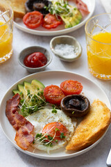 Breakfast with fried egg, tomatoes, mushroom, bacon and avocado