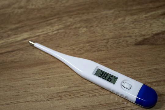 Photo of thermometer with blue handle and white color showing 38 degrees. High fever indicator.