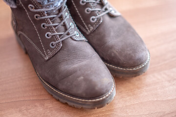 Close up of a pair of women's brown ankle boots on a wooden floor